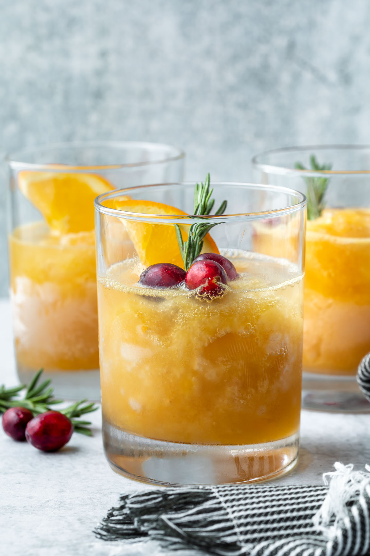 brandy slush in a glass garnished with cranberries, orange and rosemary
