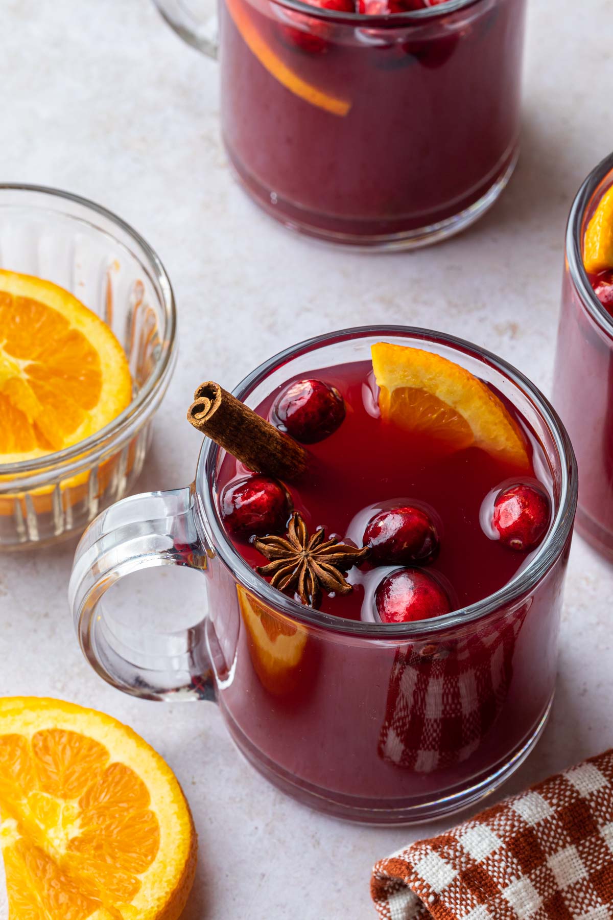 A glass mug of non alcoholic mulled wine garnished with orange slice, fresh cranberries, star anise and a cinnamon stick.