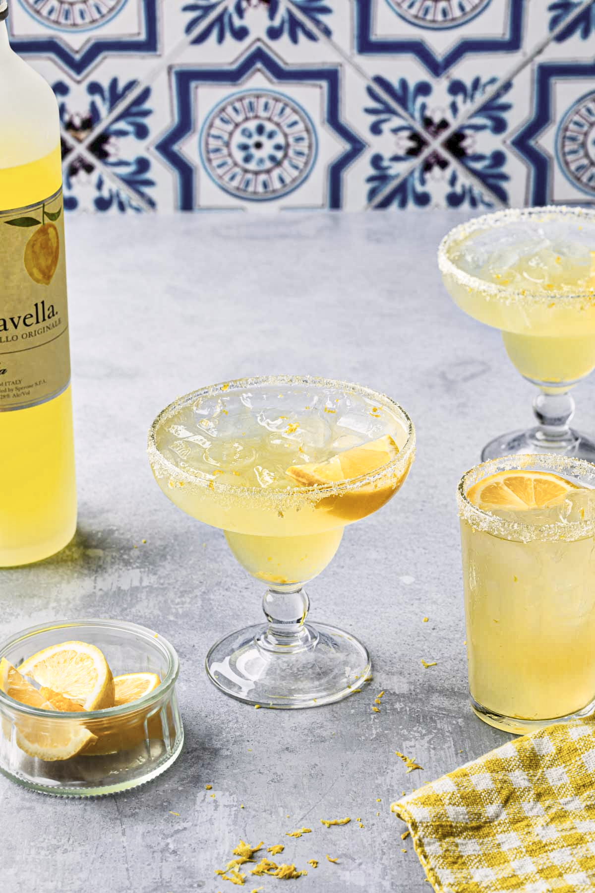 Limoncello margaritas rimmed with sugar and lemon zest, garnished with lemon wedges.