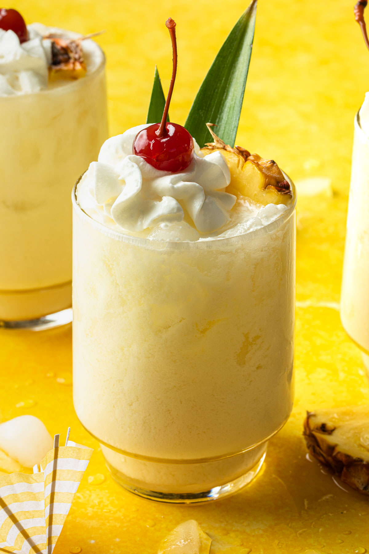 Pina Colada with Coconut Milk in a glass garnished with a pineapple wedge, whipped topping and a cherry. 
