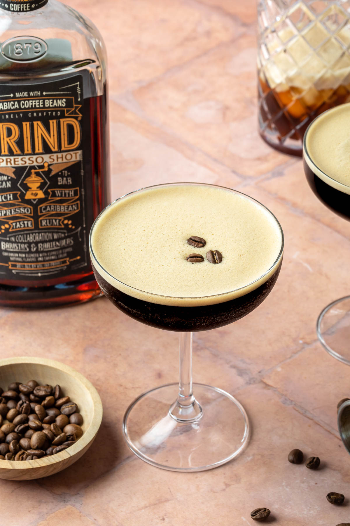 A tequila espresso martini in a coupe glass with a few espresso beans floating on top of the espresso foam. 