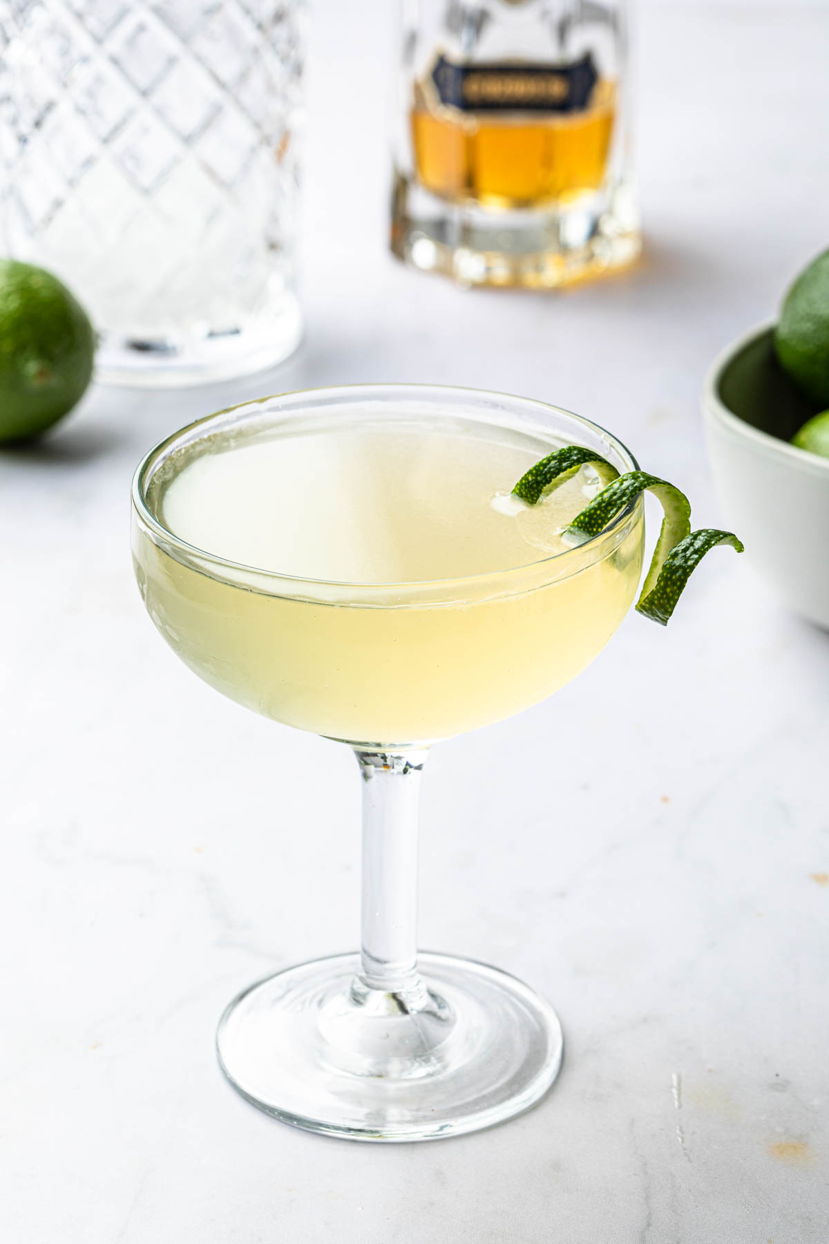 A gimlet in a coupe glass with a twist of lime. 