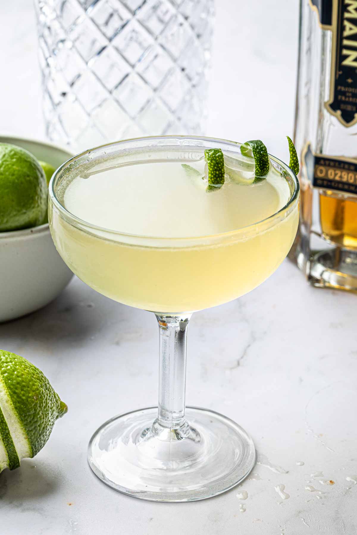 A french gimlet in a coupe glass with a twist of lime. 