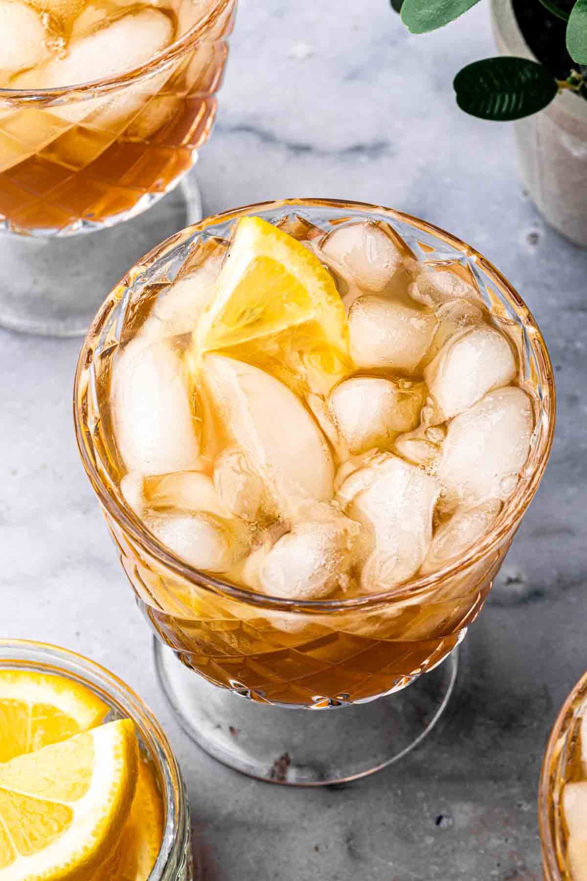 Close up of a vodka iced tea in a fancy glass, garnished with a lemon wedge. 