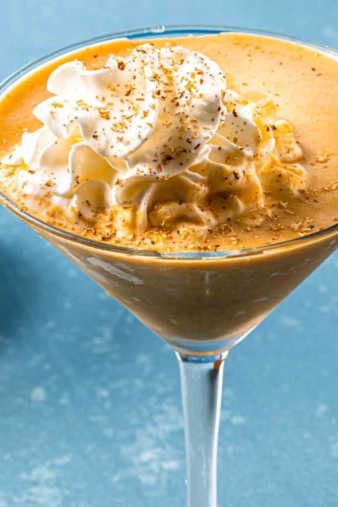 Close up of a pumpkin martini with whipped cream and grated nutmeg on top. 