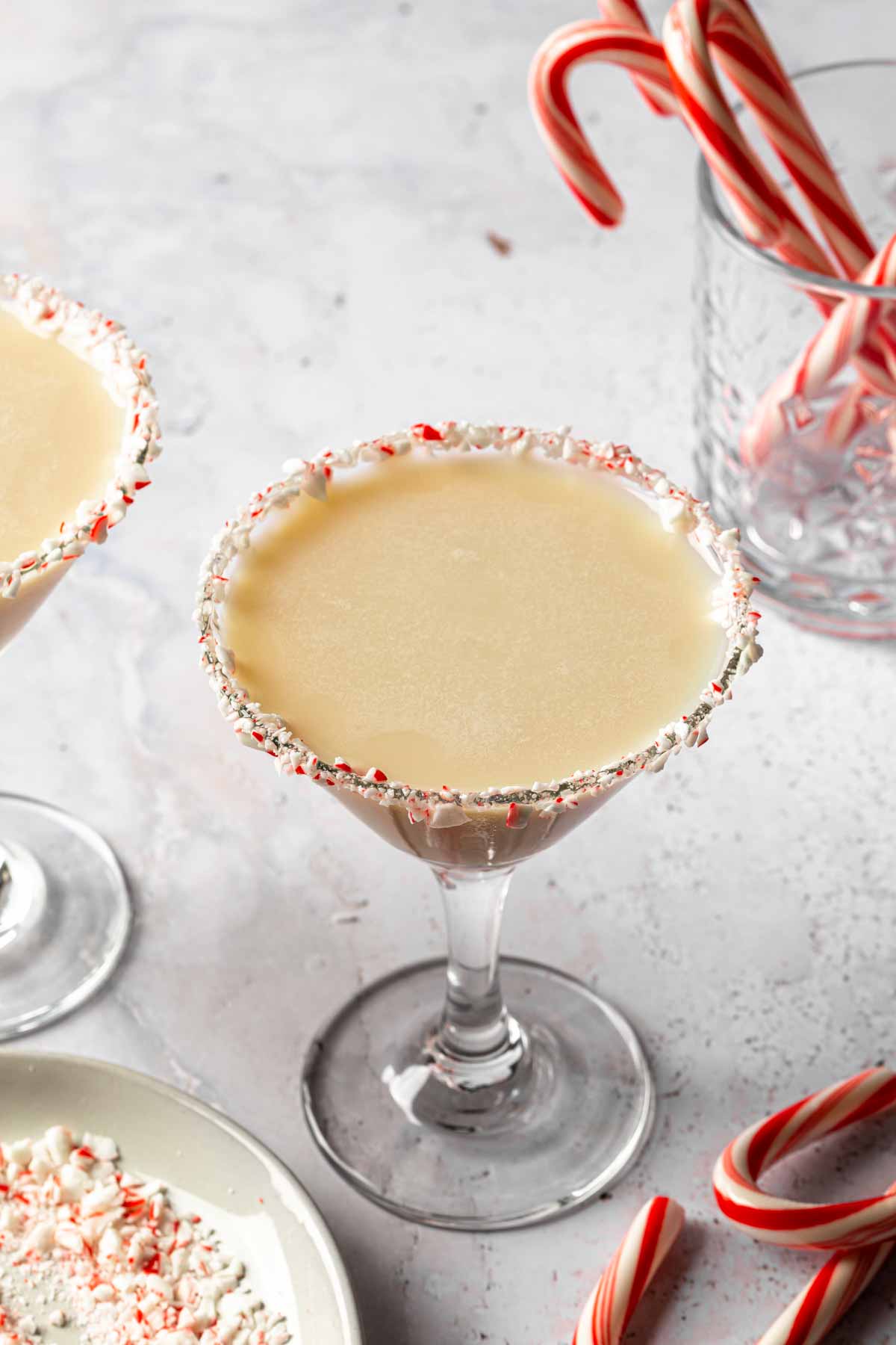 A candy cane martini in a glass rimmed with peppermint pieces. 