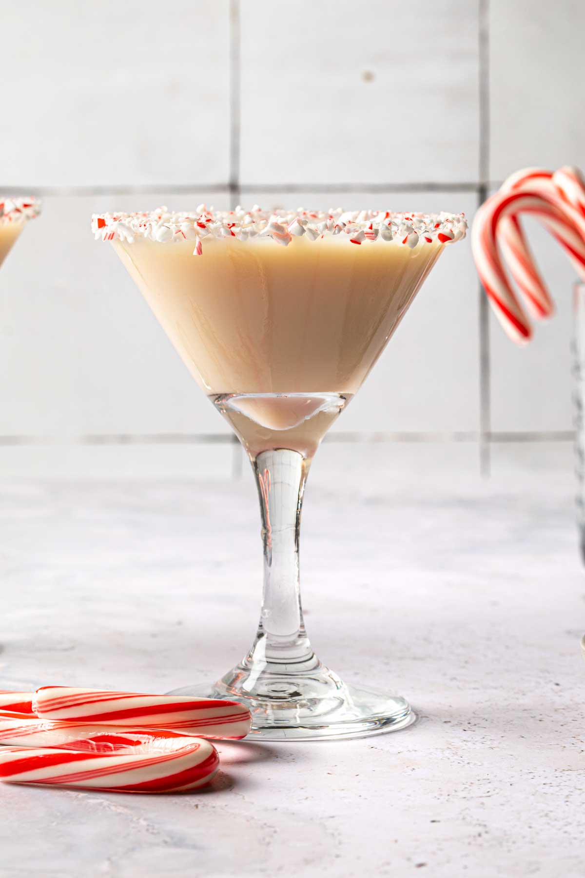 Candy cane martini in a martini glass rimmed with crushed candy canes. 
