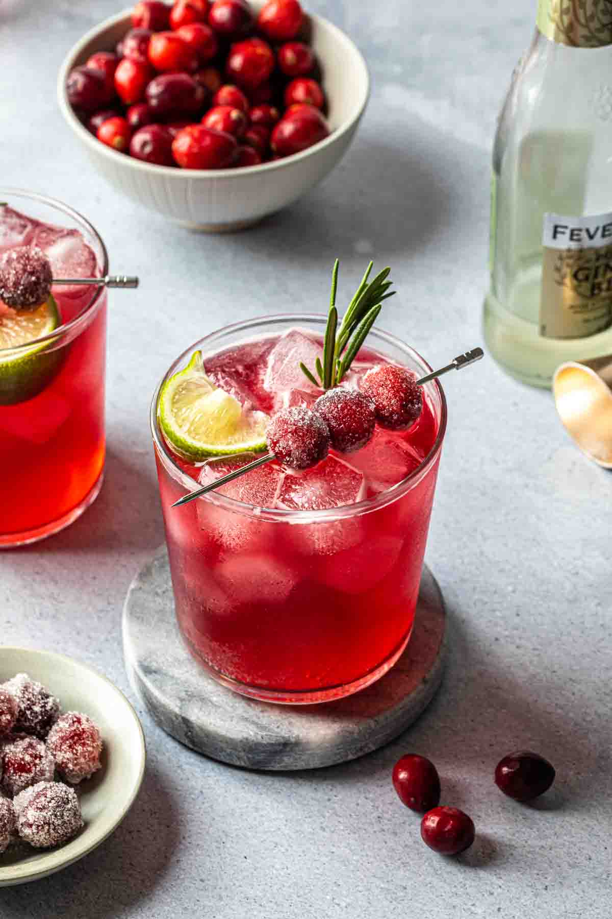 A christmas gin cocktail garnished with sugared cranberries and a sprig of fresh rosemary. 