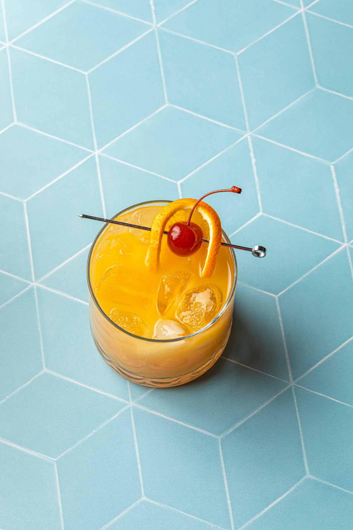 Overhead of an amaretto stone sour with a cherry and orange garnish. 