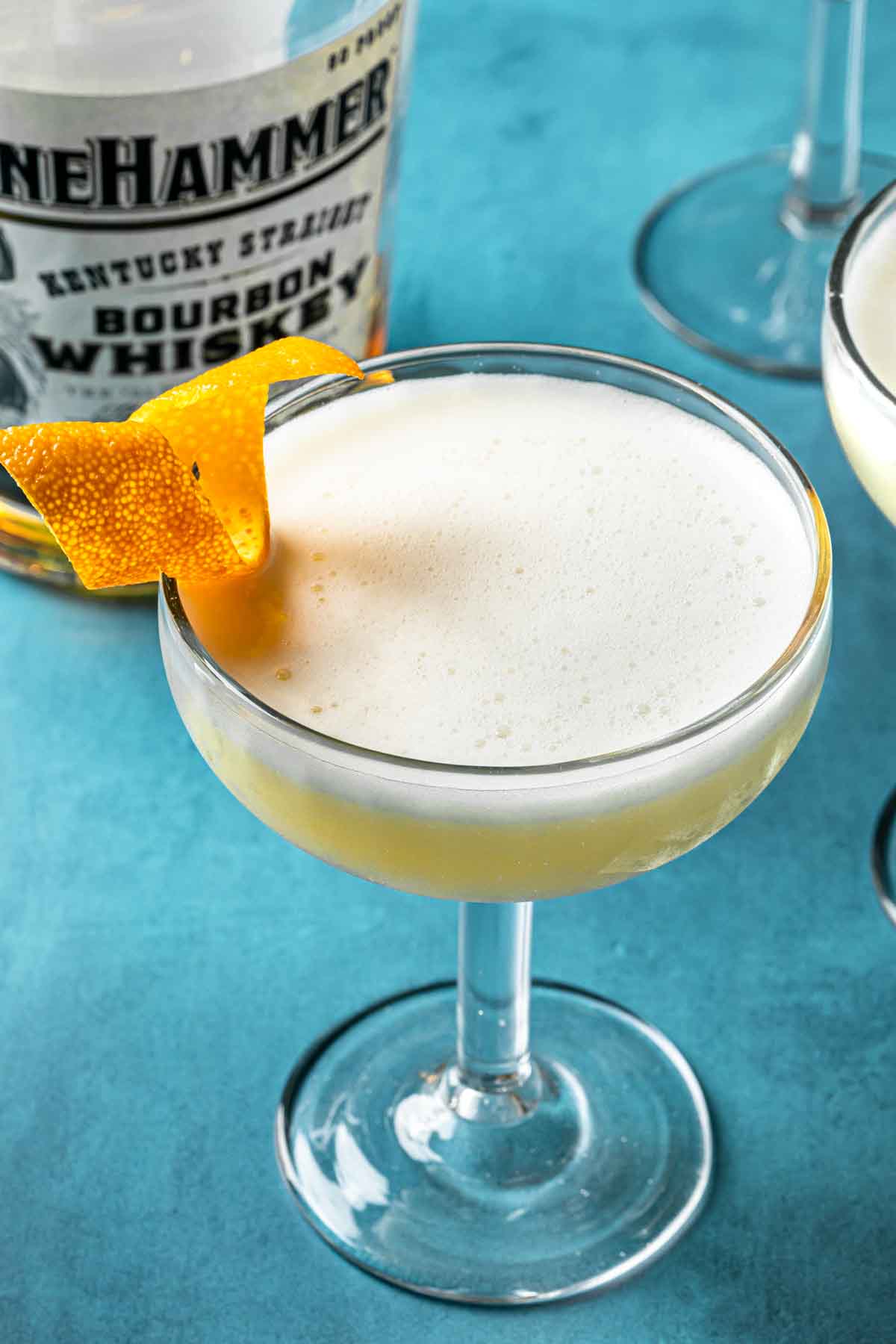 A boston sour in a coupe glass, garnished with an orange twist. 