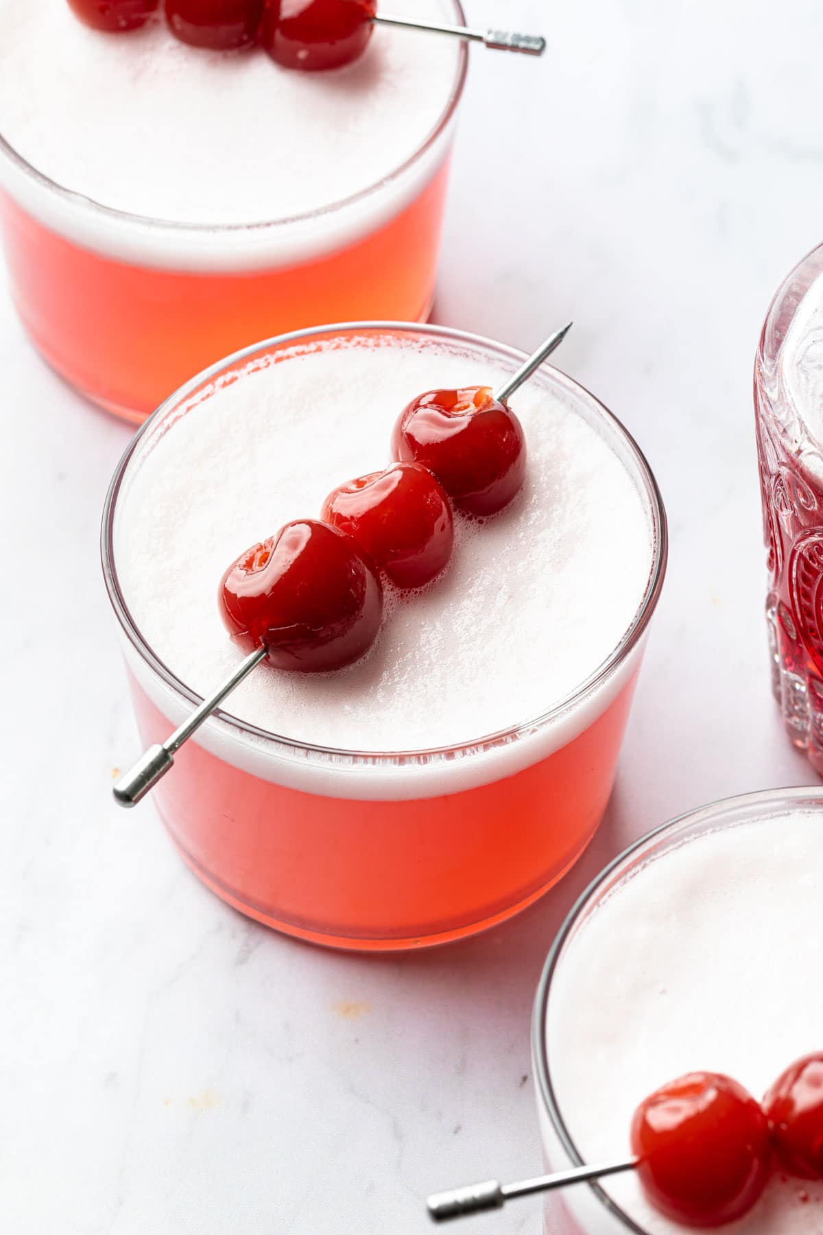 Vodka sours in glasses garnished with cherries. 