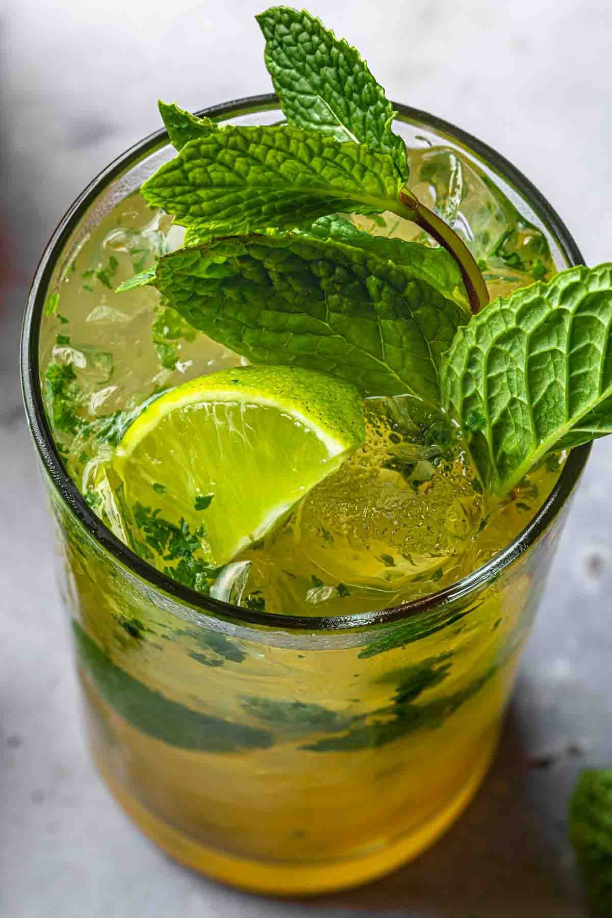 Close up of a dark rum mojito garnished with mint and lime. 