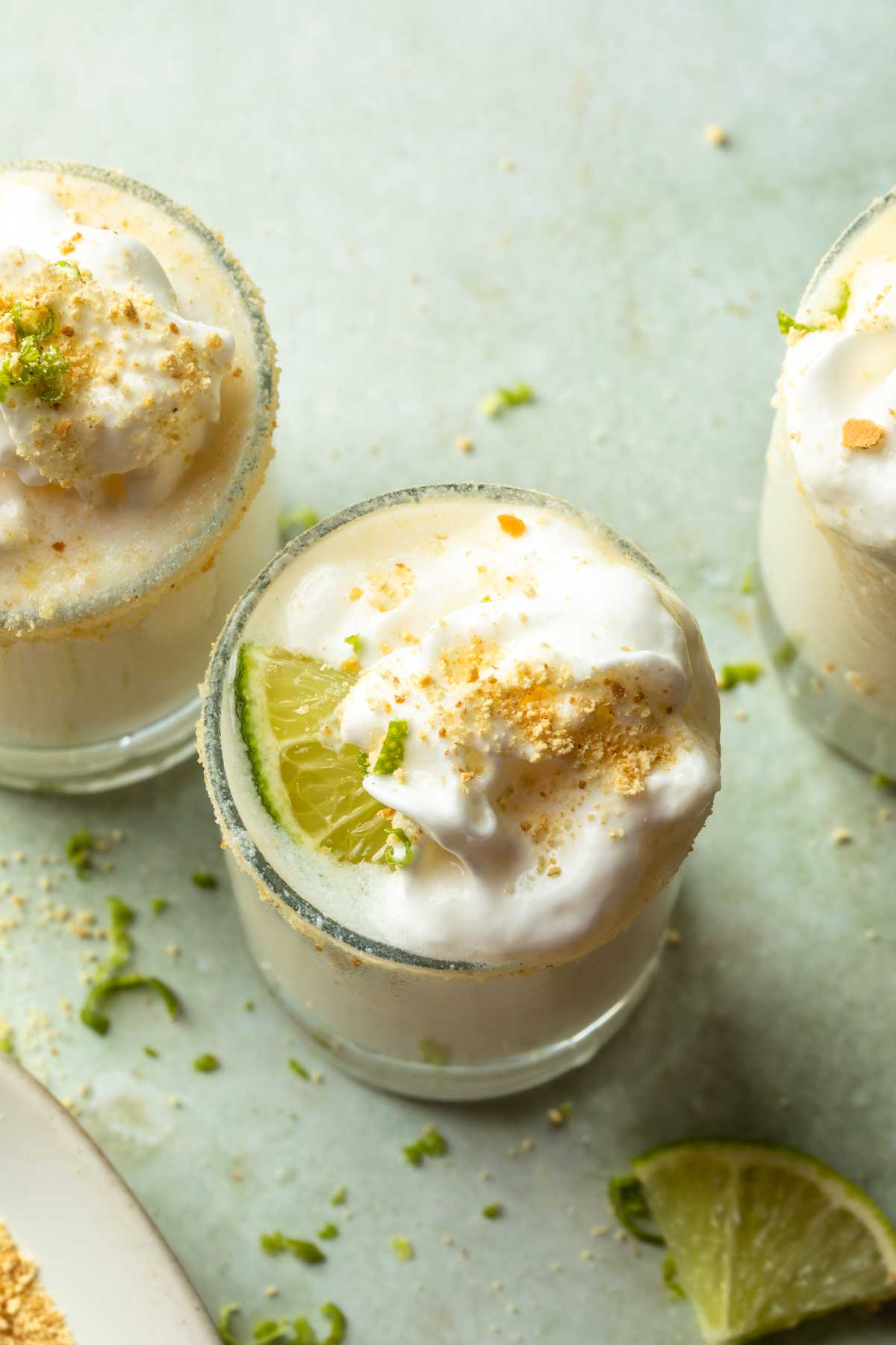 A shot glass topped with whipped cream and graham cracker crumbs. 