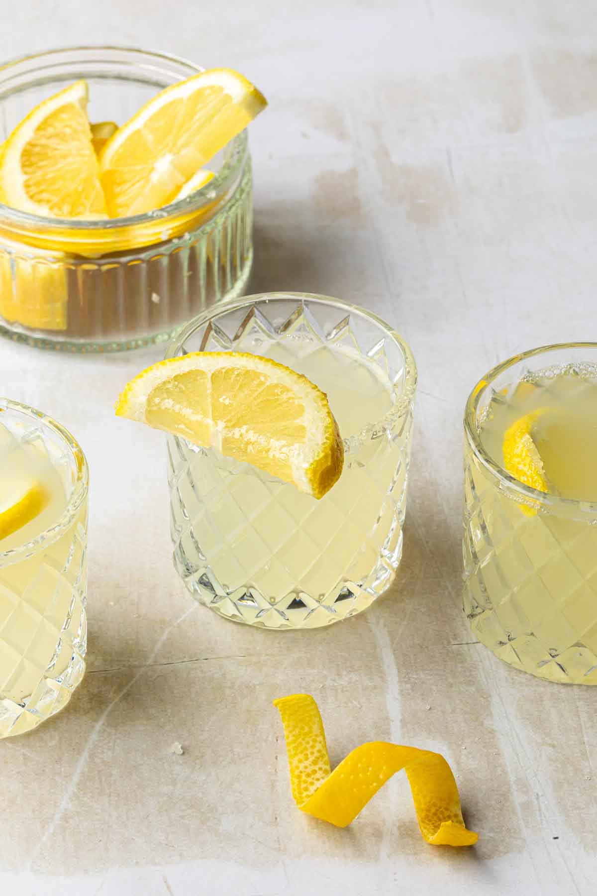 A few shot glasses full of shots with sugared lemons topping the glasses, one has a lemon in it. 