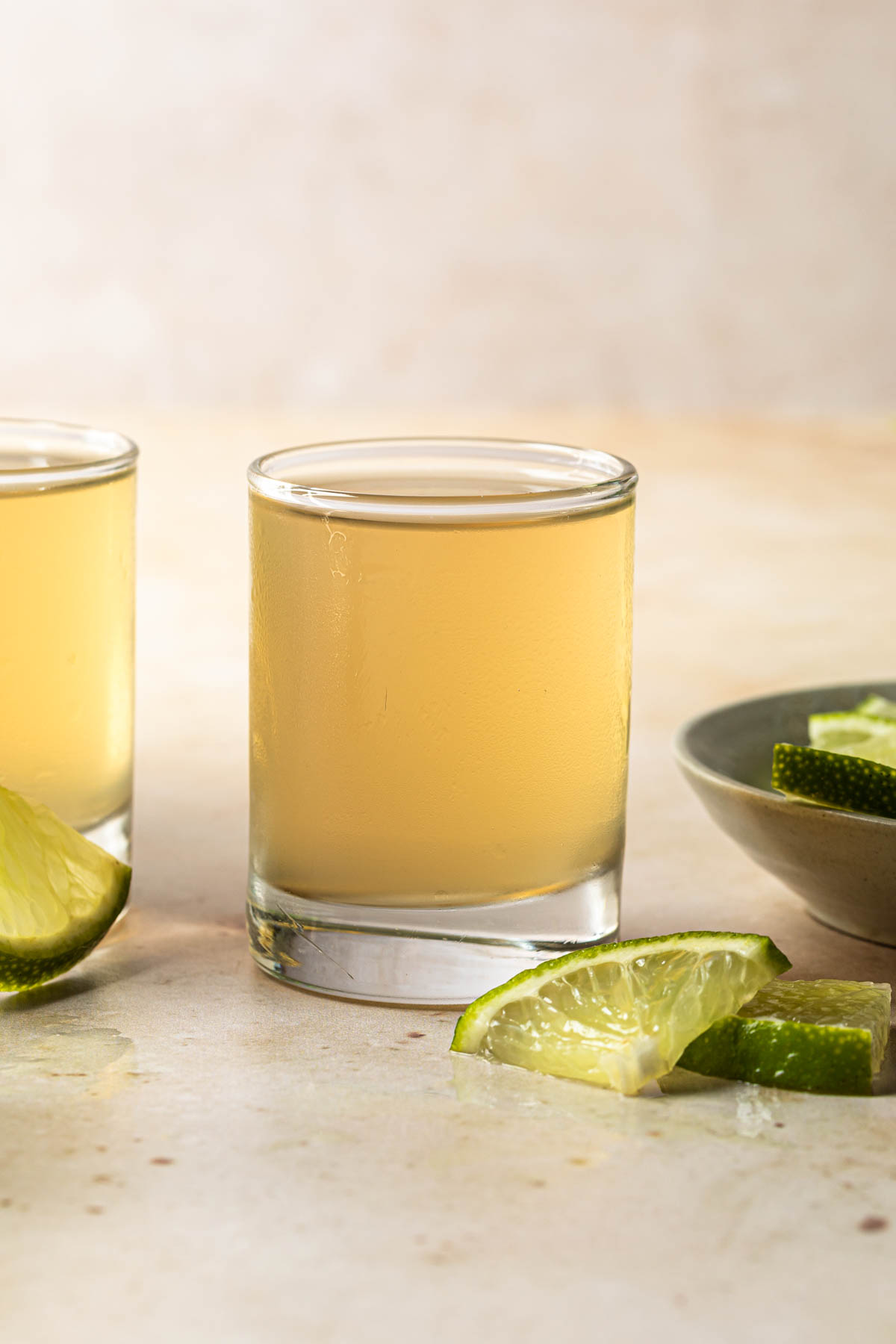 A couple shots, in shot glasses with lime wedges surrounding them. 