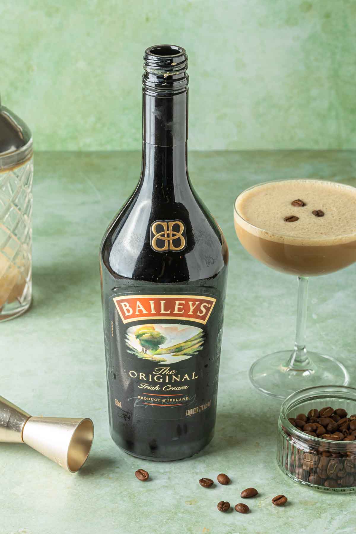 A bottle of Baileys Irish cream with a creamy martini in the background. 