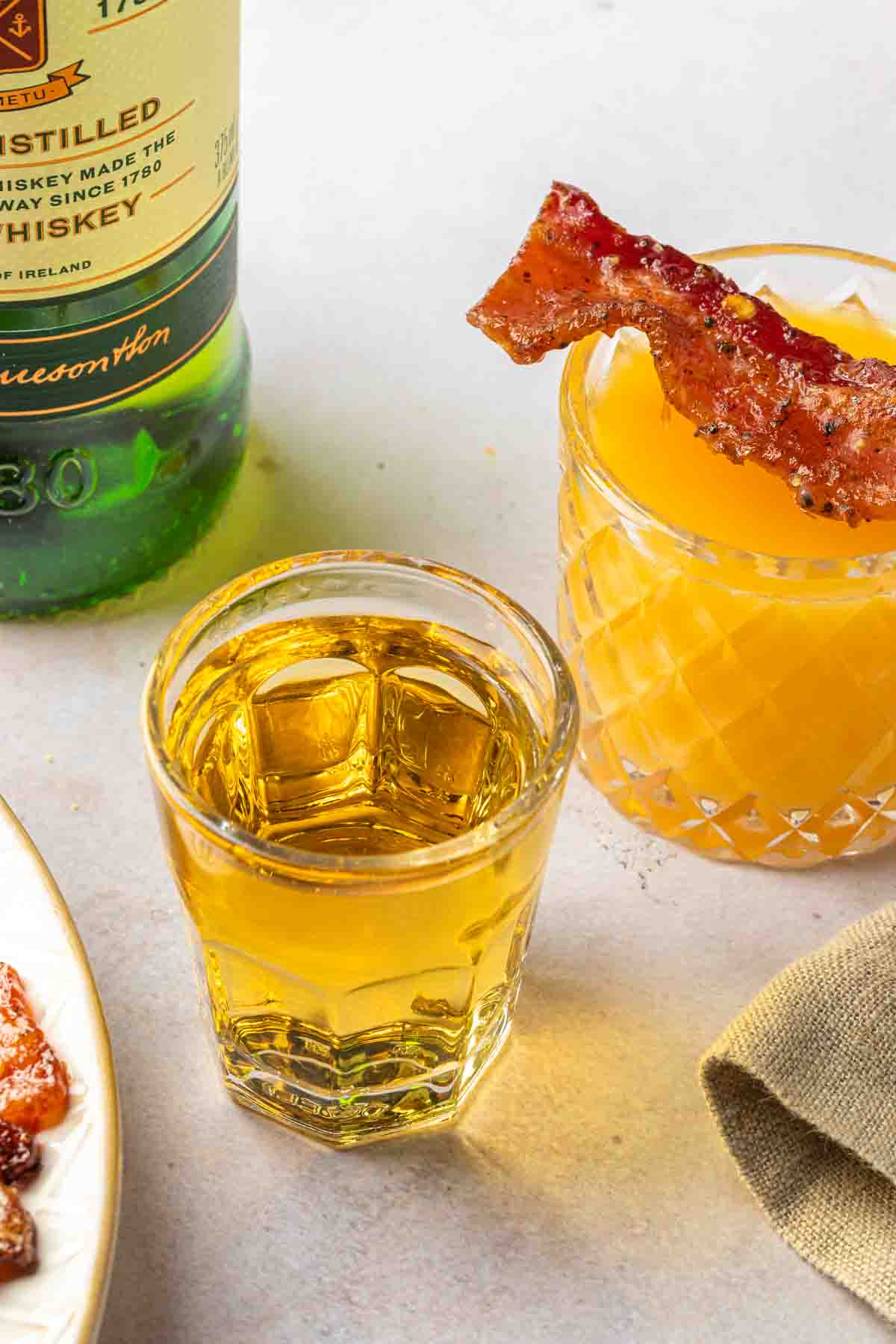 An Irish breakfast shot with an orange juice chaser, garnished with a slice of bacon. 