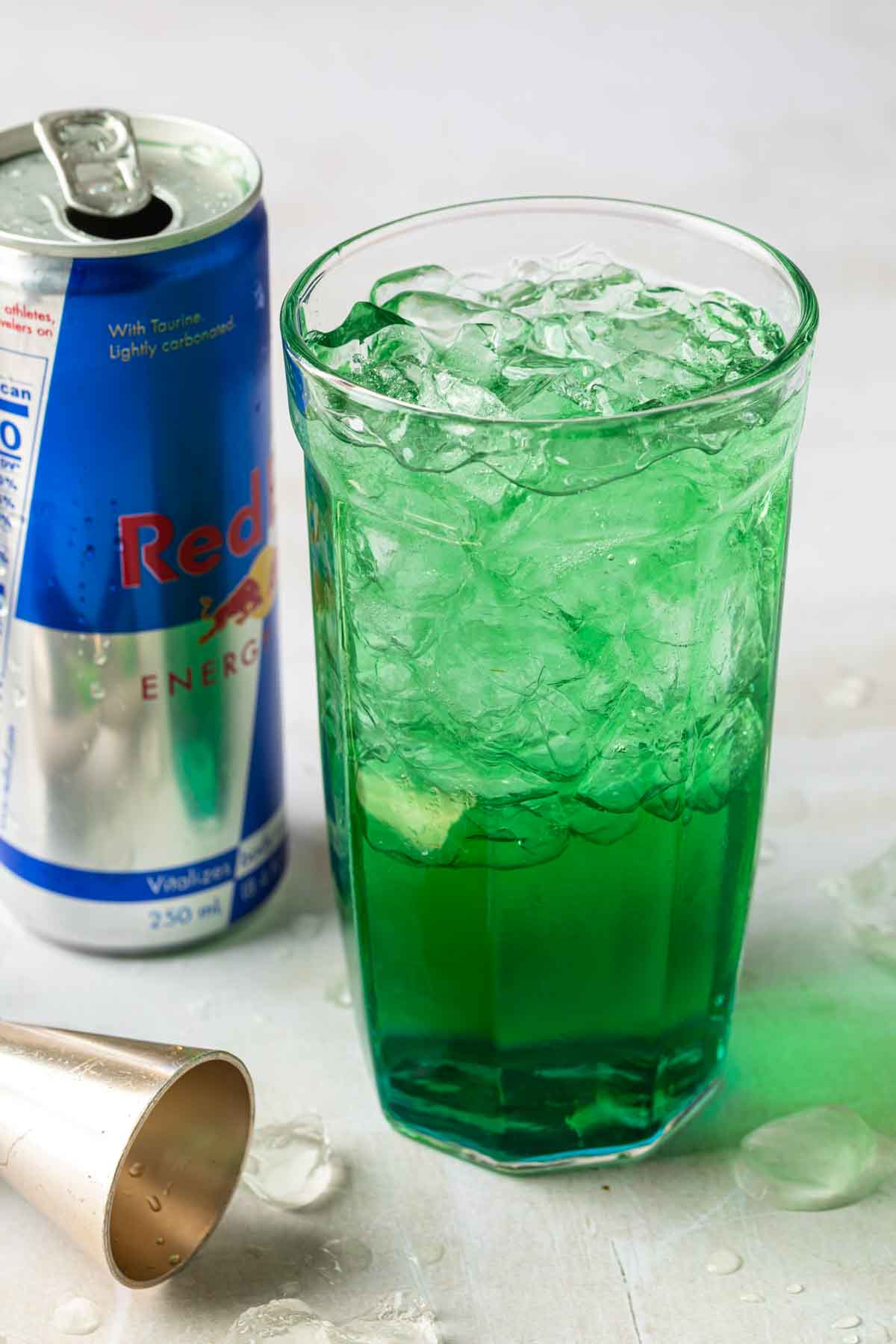 Close up of a green Irish trash can drink, next to a can of red bull. 