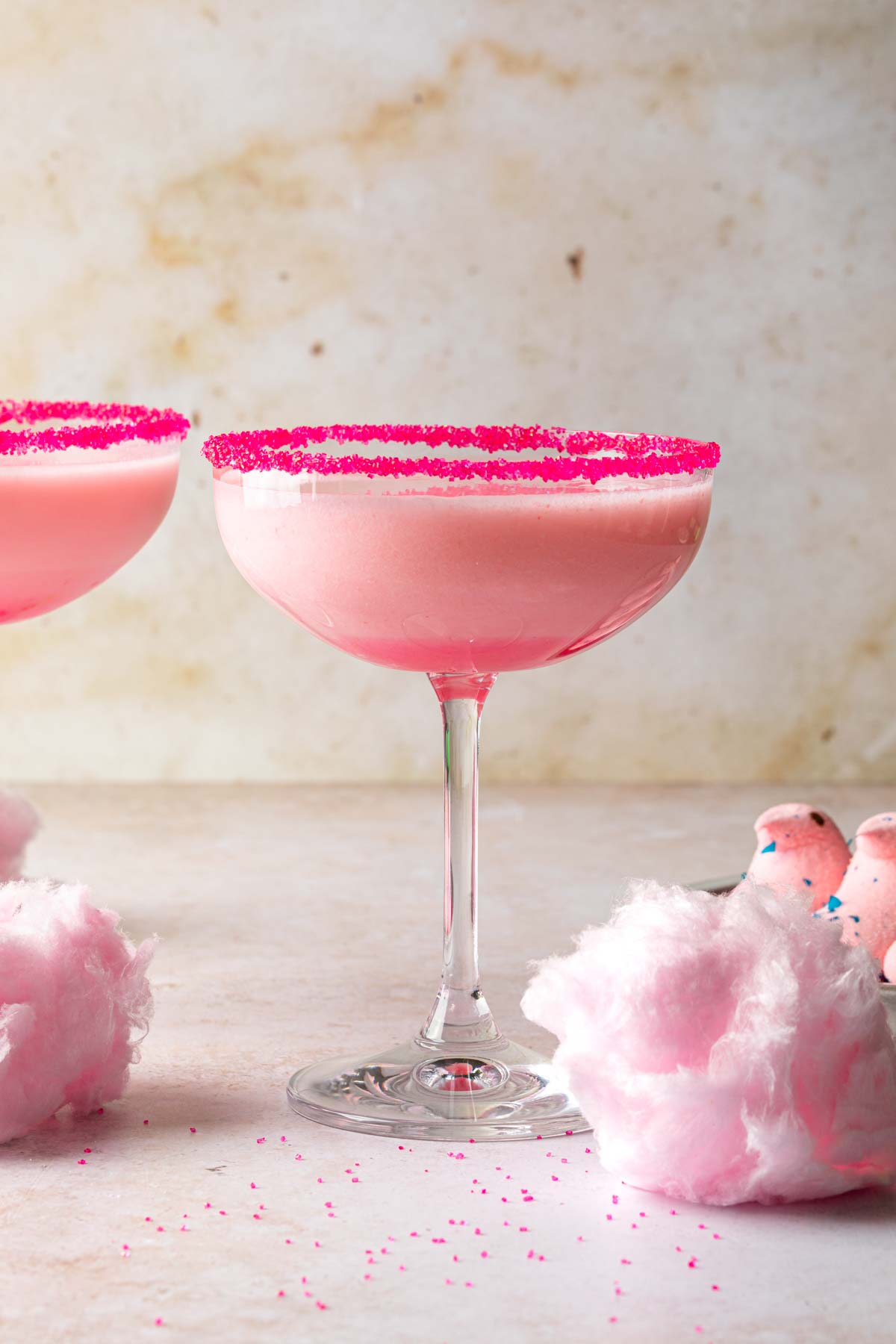A couple of pink martinis garnished with cotton candy and peeps. 