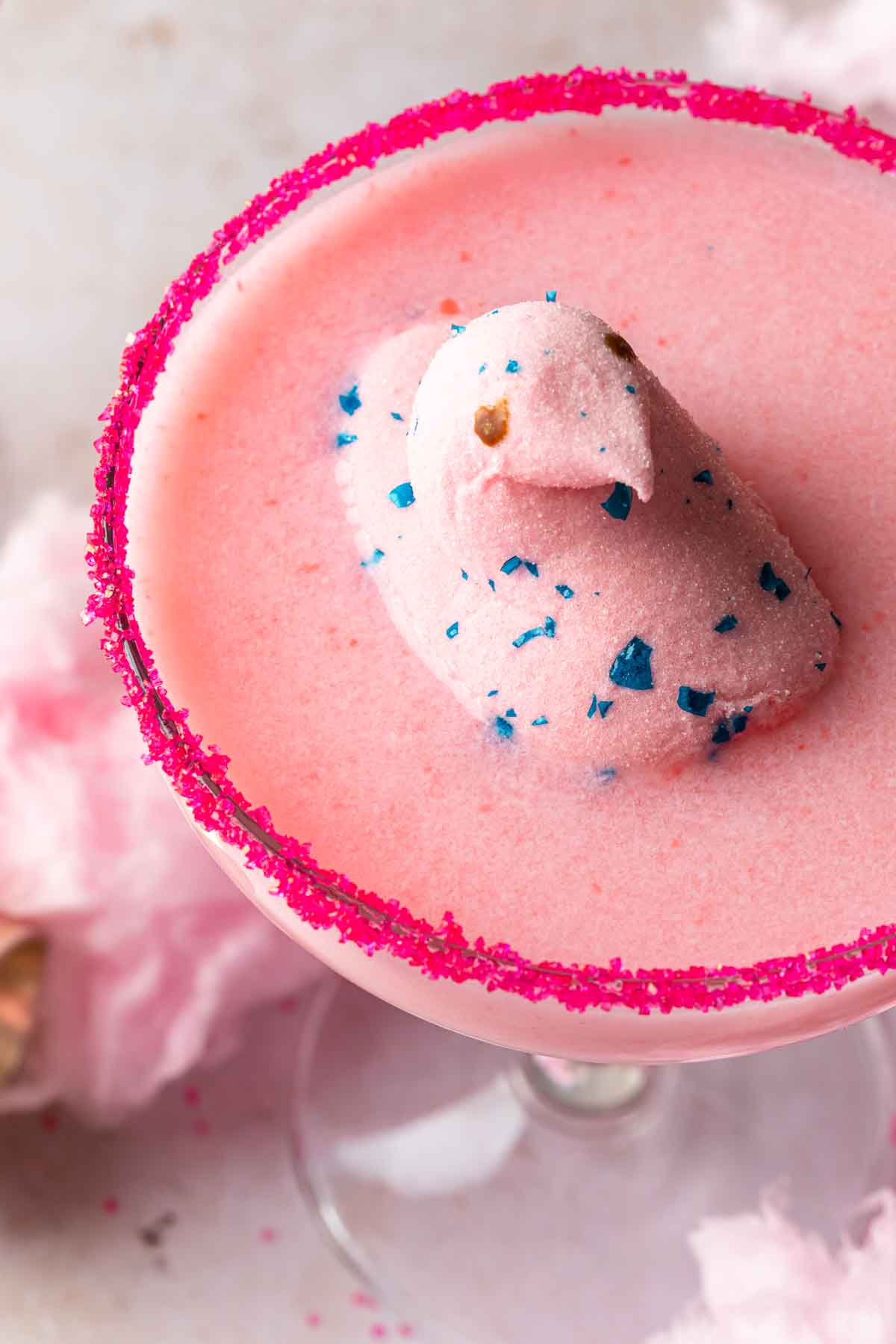 Close up of a pink easter peep floating in a hot pink sugar rimmed creamy cocktail. 