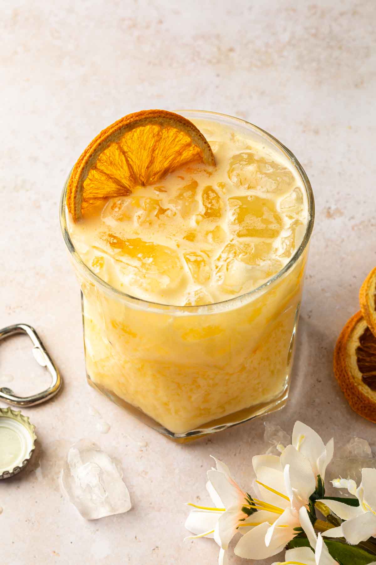 A creamy orange drink made with passion fruit syrup, garnished with a dried orange wheel. 