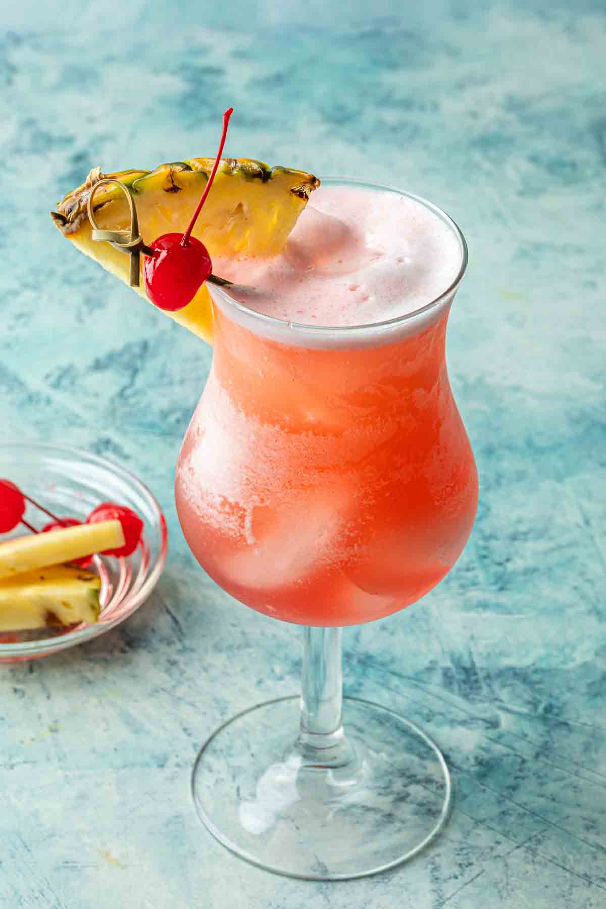 A tropical cocktail made with coconut rum, pineapple juice and cranberry juice, garnished with a pineapple and a cherry. 