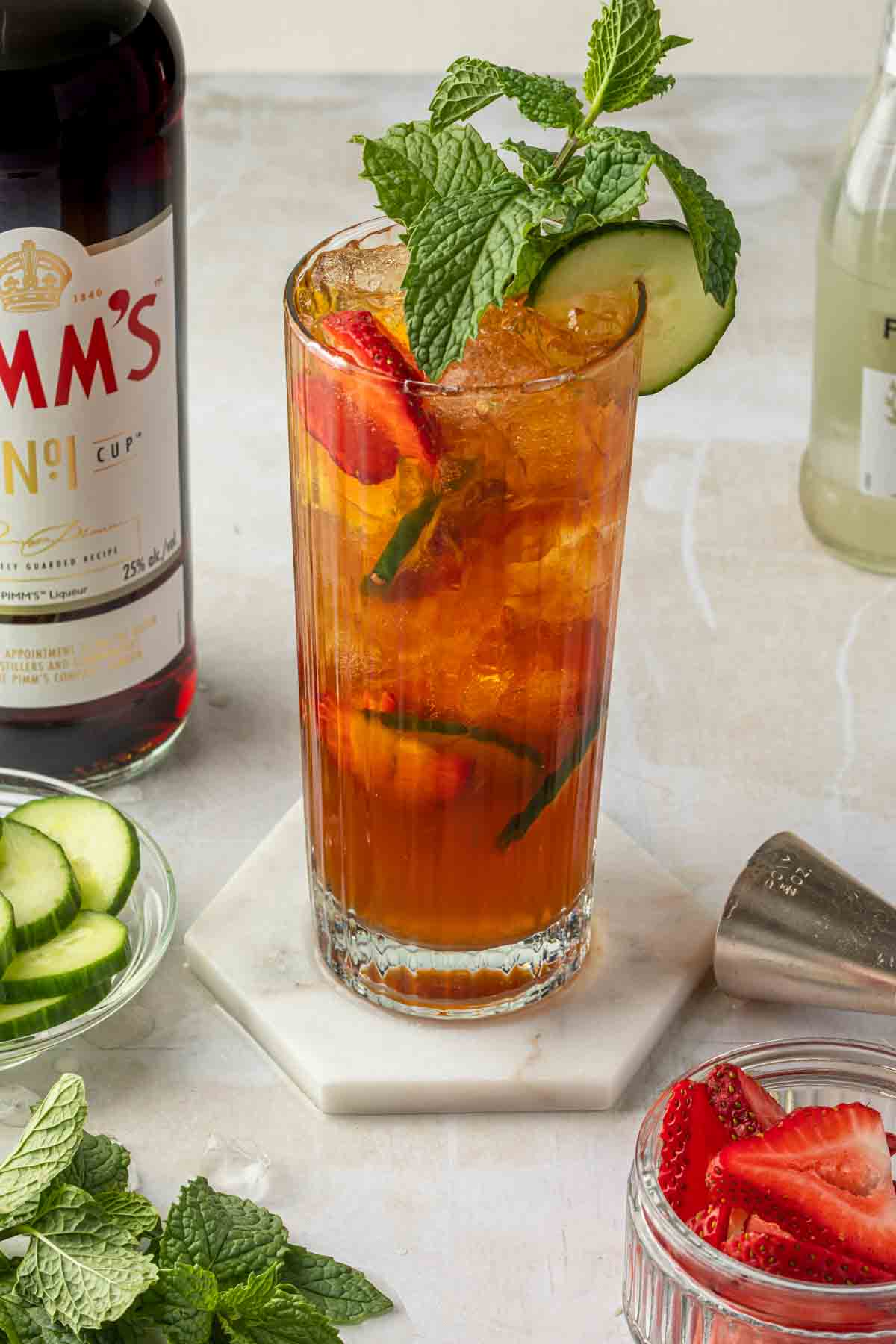 A Pimm's Cup cocktail, garnished with mint, cucumber and strawberries. 