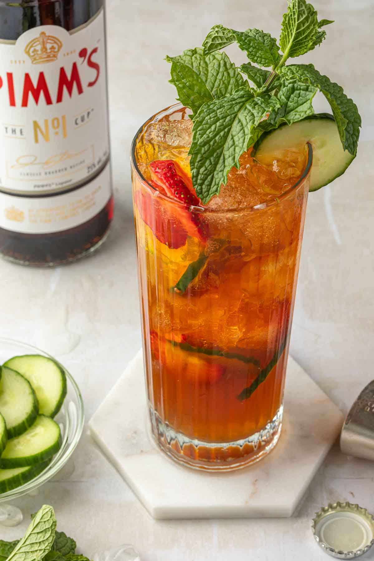 A Pimm's cup in a highball glass garnished with mint leaves and cucumber. 