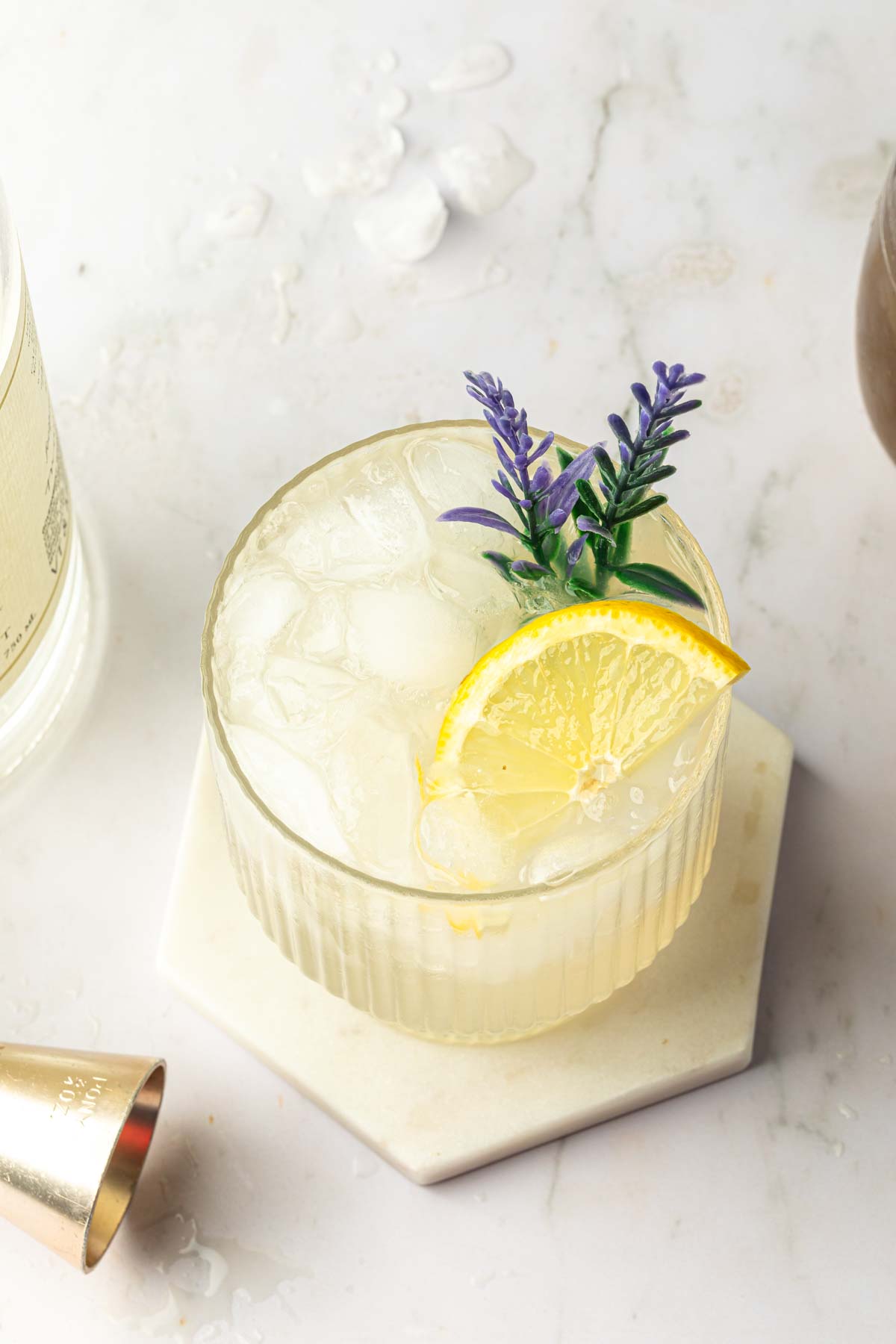 A lavender lemonade gin cocktail garnished with lavender flowers and a lemon wedge.