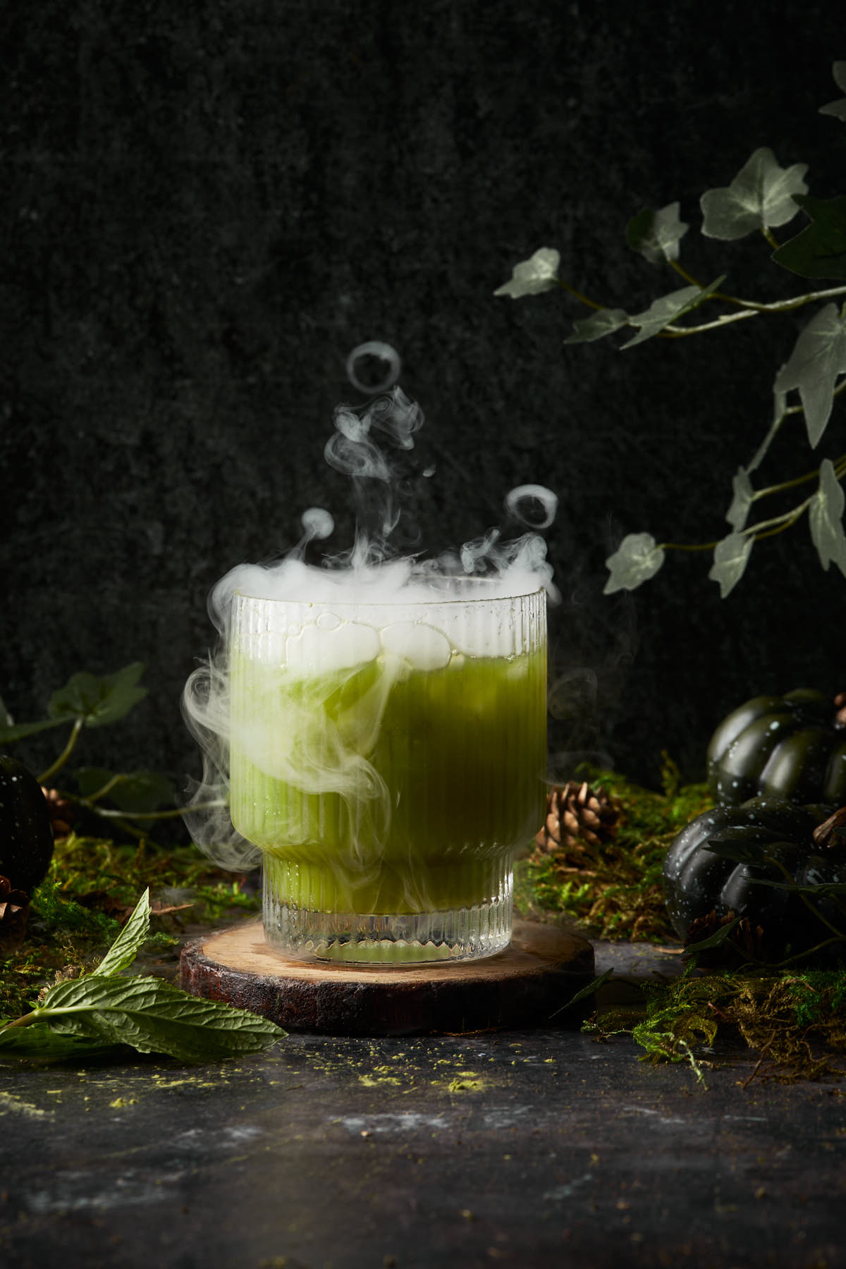 A swamp water cocktail with smoke coming bubbling out of the glass. 