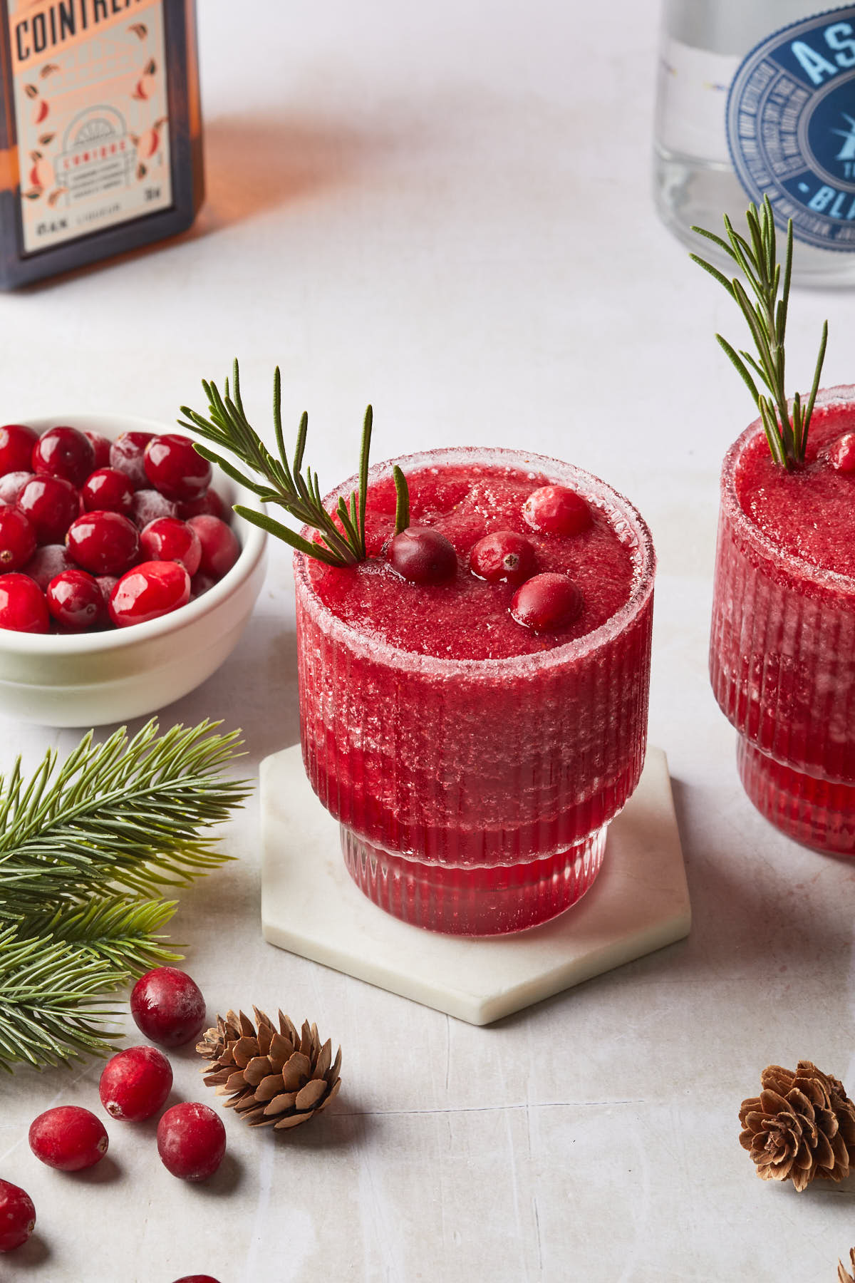A mistletoe margarita garnished with cranberries and a rosemary sprig. 
