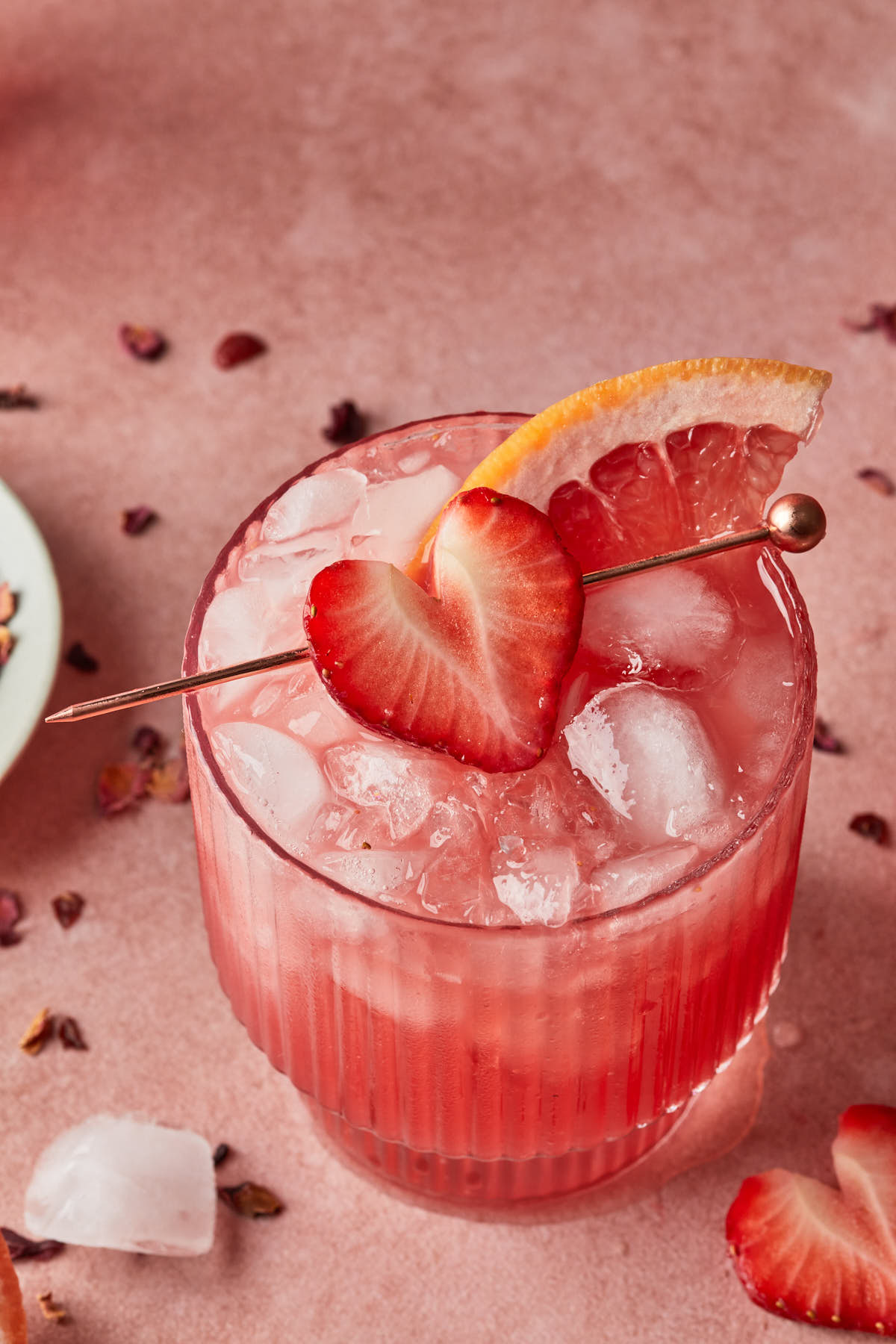 Close up of a strawberry grapefruit cocktail, garnished with a strawberry heart. 