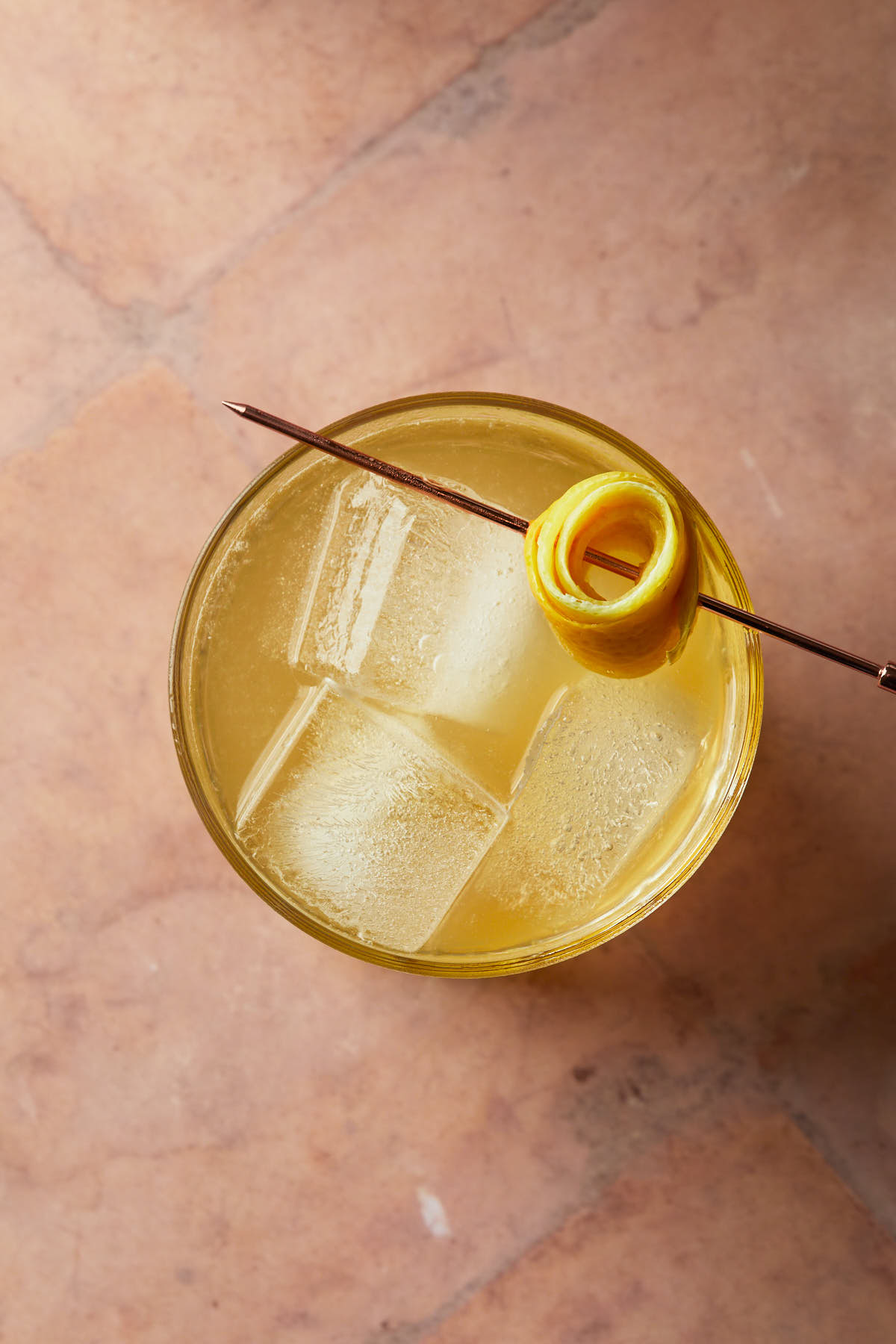 Close up of a cocktail garnished with a lemon peel rosette. 