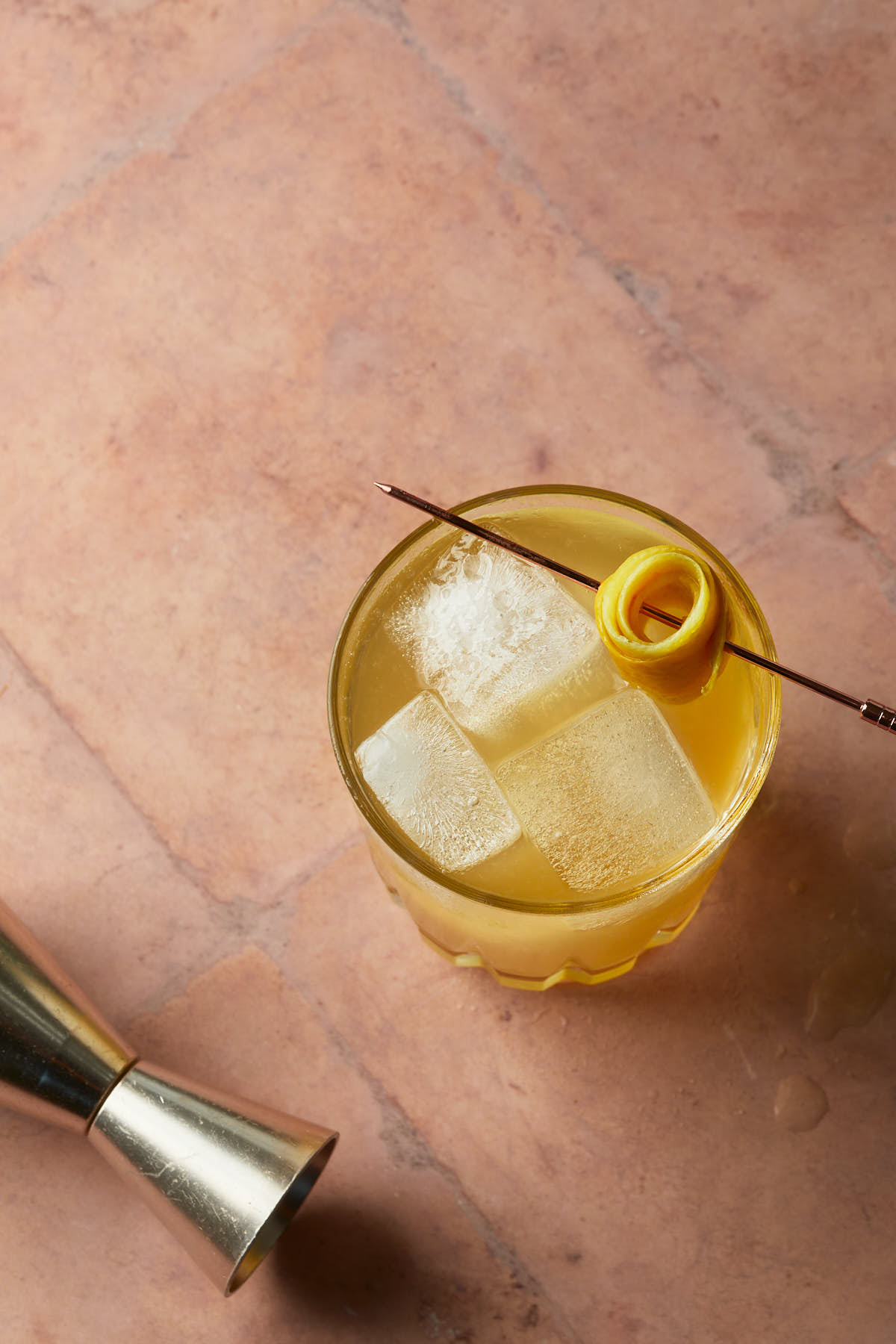 A penicillin cocktail garnished with a lemon peel rose. 